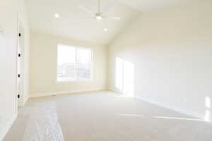 Carpeted spare room featuring ceiling fan and lofted ceiling