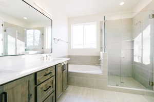 Bathroom featuring vanity, shower with separate bathtub, and tile patterned flooring