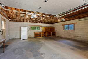 Garage with a garage door opener and white refrigerator