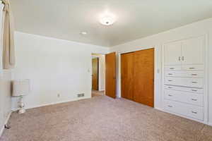 Unfurnished bedroom with light carpet and a closet