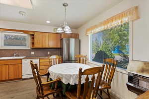 Dining room featuring light hardwood / wood-style floors, a wealth of natural light, sink, and a notable chandelier