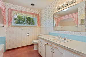 Bathroom featuring tile walls, toilet, and vanity