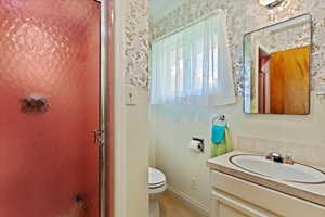 Bathroom with an enclosed shower, vanity, and toilet