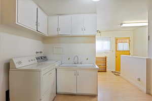 Laundry room featuring sink, light hardwood / wood-style floors, and separate washer and dryer