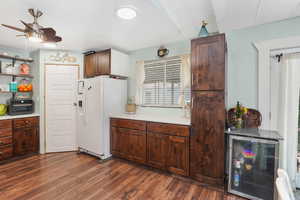 Kitchen featuring ceiling fan, dark hardwood / wood-style flooring, white fridge with ice dispenser, and beverage cooler