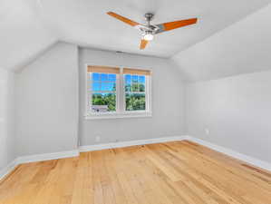 2nd floor bedroom with ceiling fan, light wood-type flooring, and lofted ceiling