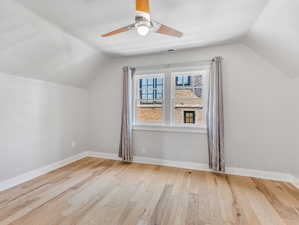 2nd floor bedroom with ceiling fan, light wood-type flooring, and lofted ceiling