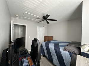 Carpeted bedroom featuring ceiling fan and a textured ceiling