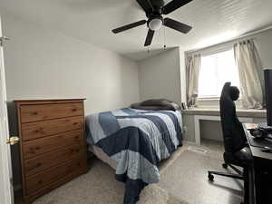 Bedroom with ceiling fan, a textured ceiling, and light colored carpet