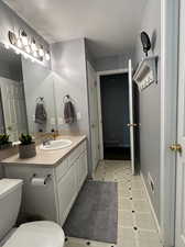 Bathroom featuring tile patterned floors, a textured ceiling, vanity, and toilet