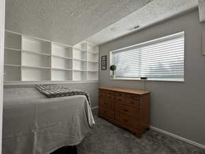 Bedroom featuring dark colored carpet and a textured ceiling