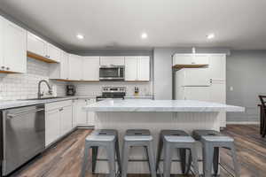 Kitchen featuring sink, stainless steel appliances, dark wood-type flooring, and a kitchen island