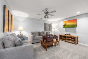 Carpeted living room featuring ceiling fan