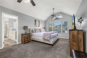 Bedroom featuring ceiling fan, lofted ceiling, hardwood / wood-style flooring, and ensuite bath