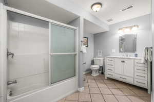 Full bathroom featuring combined bath / shower with glass door, toilet, tile patterned flooring, and vanity