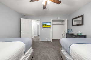 Carpeted bedroom with ceiling fan and a closet