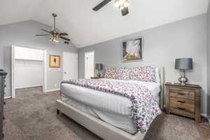 Carpeted bedroom with ceiling fan, a closet, lofted ceiling, and a walk in closet