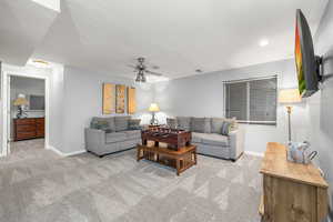 Carpeted living room featuring ceiling fan and a textured ceiling