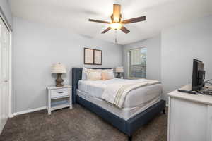 Carpeted bedroom with ceiling fan and a closet