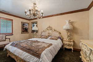 Bedroom with a textured ceiling, carpet floors, crown molding, and a chandelier