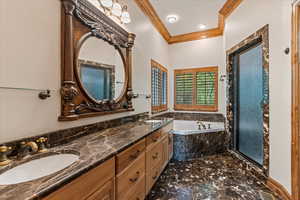 Bathroom featuring crown molding, double vanity, and separate shower and tub