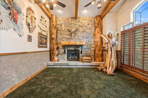 Unfurnished living room with ceiling fan, beam ceiling, carpet flooring, and a fireplace