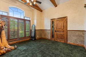 Carpeted spare room featuring beam ceiling, ceiling fan, and high vaulted ceiling