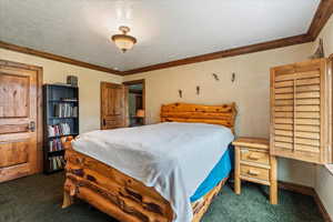 Bedroom with carpet floors, ornamental molding, and a textured ceiling