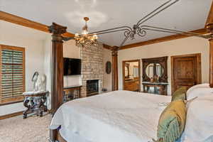 Carpeted bedroom with a fireplace and an inviting chandelier