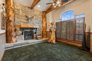 Unfurnished living room with a fireplace, carpet flooring, ceiling fan, and beam ceiling