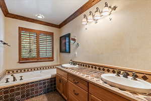 Bathroom featuring a relaxing tiled tub, double vanity, and ornamental molding