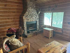 Living room featuring hardwood / wood-style flooring, lofted ceiling, wood ceiling, and a stone fireplace