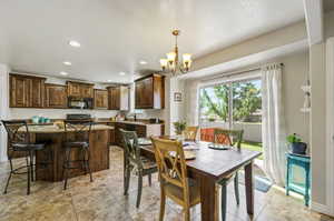 Tiled dining area with sink, a textured ceiling, and an inviting chandelier