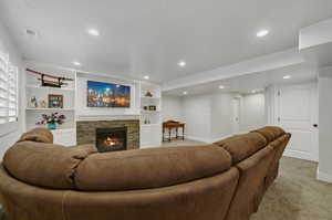 Living room with carpet floors, built in features, and a fireplace