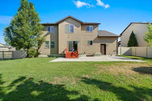 Back of property with a lawn and a patio area