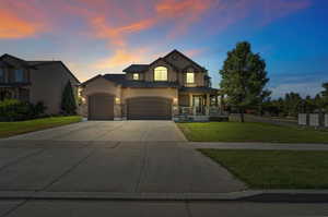 View of front of home featuring a garage, a yard, and a porch