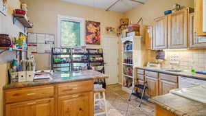 Kitchen with sink, stone counters, white dishwasher, decorative backsplash, and light tile patterned floors