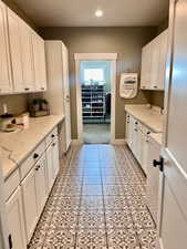 Laundry room featuring light tile patterned flooring and white cabinetry