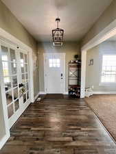 Entrance foyer featuring dark colored carpet, plenty of natural light, french doors, and a chandelier