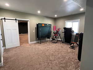 Workout area with light carpet and a barn door