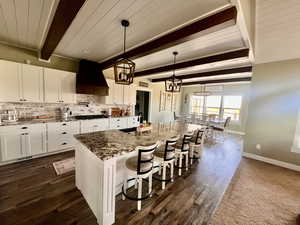 Kitchen featuring sink, beamed ceiling, a kitchen island with sink, a breakfast bar area, and custom exhaust hood