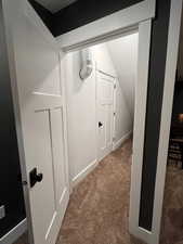 Hallway featuring vaulted ceiling and carpet floors