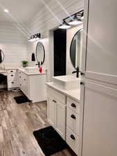 Bathroom featuring wood walls, hardwood / wood-style flooring, and double sink vanity