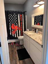 Bathroom featuring hardwood / wood-style floors, toilet, and vanity