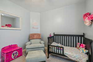 Carpeted bedroom featuring a crib