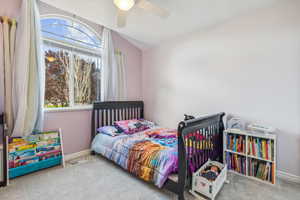 Carpeted bedroom featuring ceiling fan and lofted ceiling