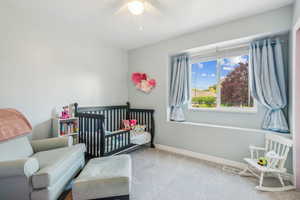 Carpeted bedroom with ceiling fan and a crib