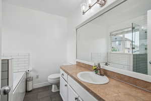 Bathroom with tile patterned floors, vanity, tiled bath, and toilet