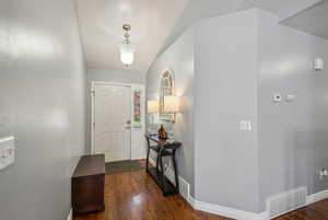 Foyer with dark hardwood / wood-style floors and vaulted ceiling