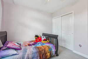 Bedroom featuring ceiling fan, a closet, and light carpet